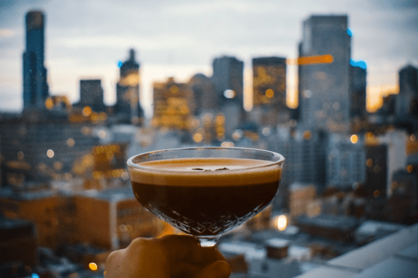 Someone holding an espresso martini in front of a city skyline