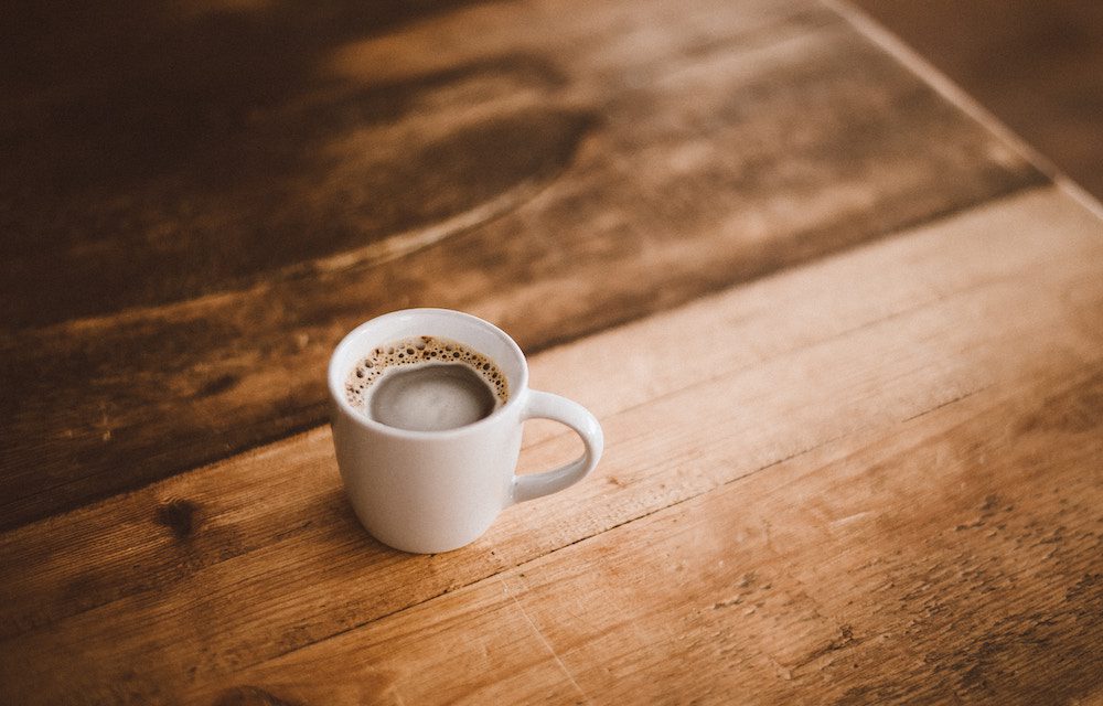 small coffee in white mug on wooden table 
