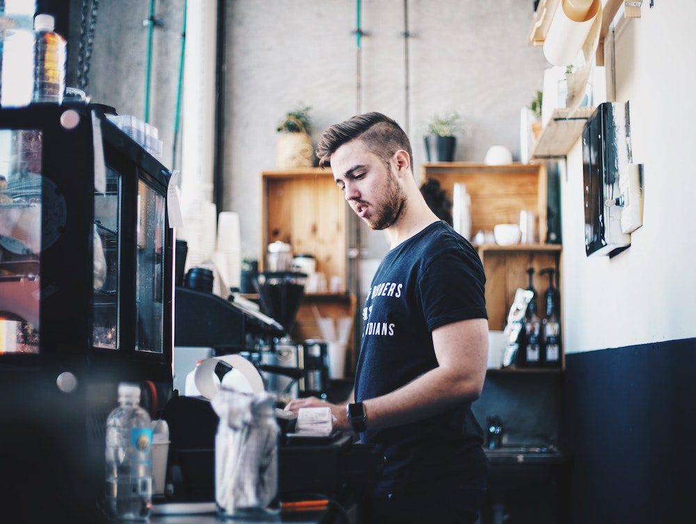 A barista making a coffee using a coffee machine 