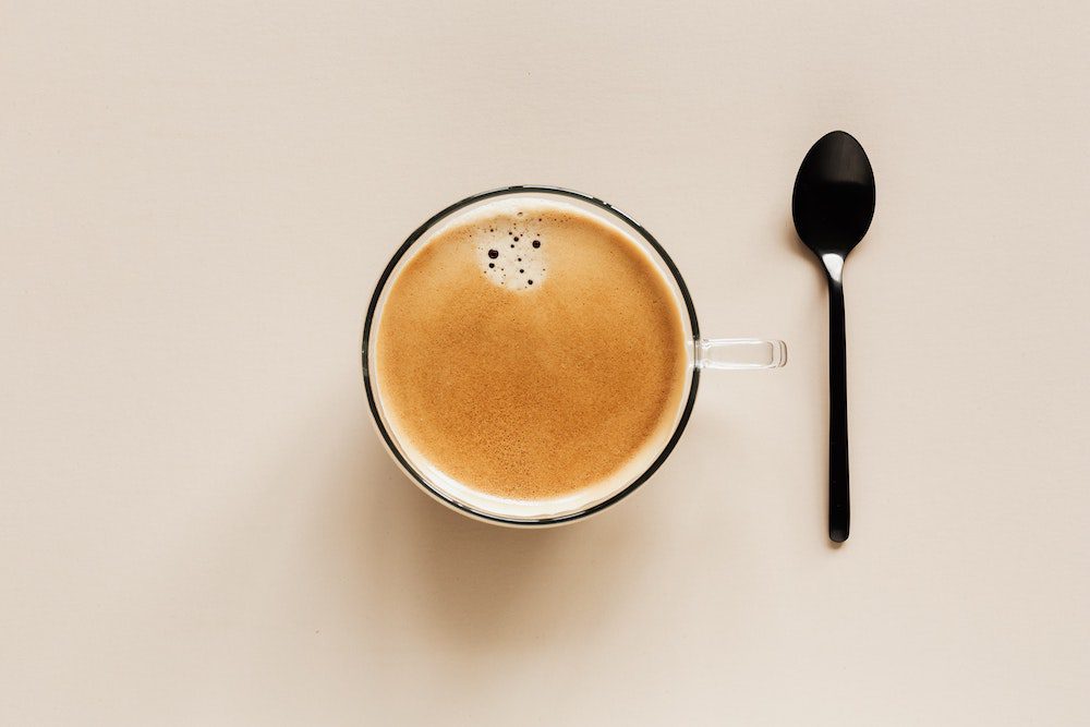 A cup of coffee next to a teaspoon