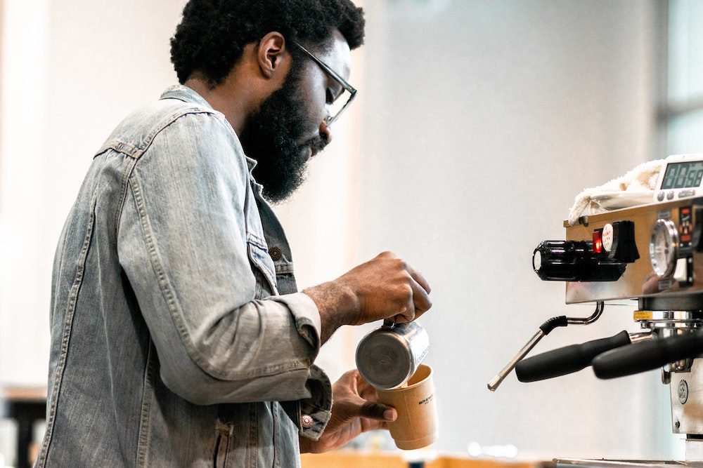 A barista concentrating on making a coffee in a coffee shop
