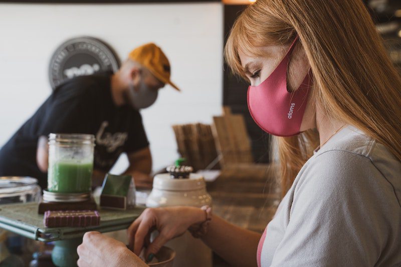 Two baristas making coffee wearing face masks
