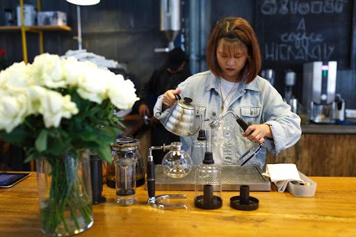 A woman in a coffee shop pouring coffee