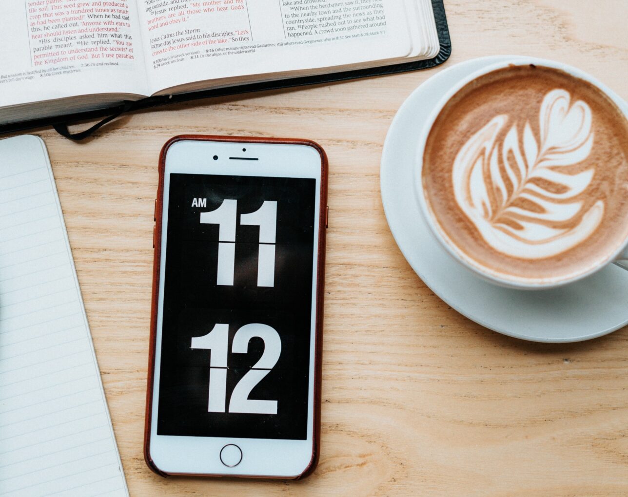 The clock app open on an iPhone next to a latte.