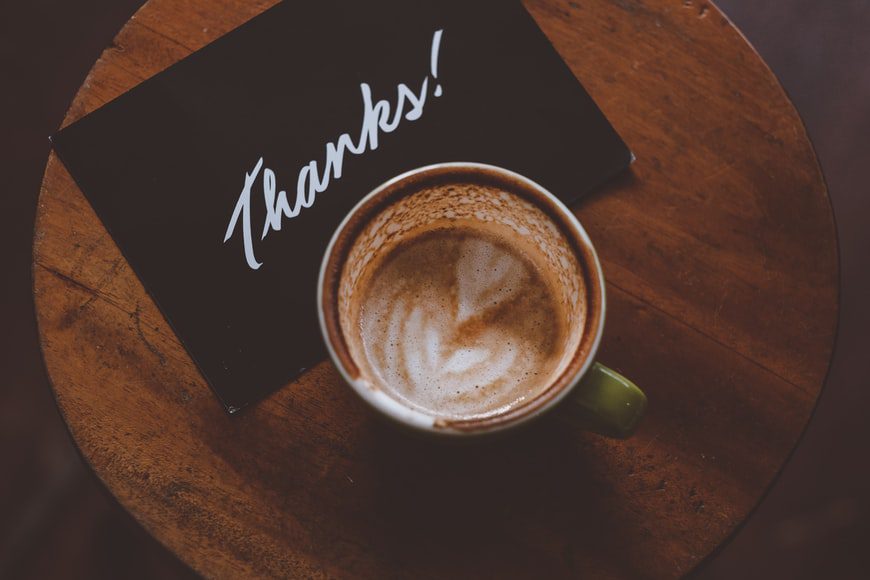 A cup of coffee with a thank you note