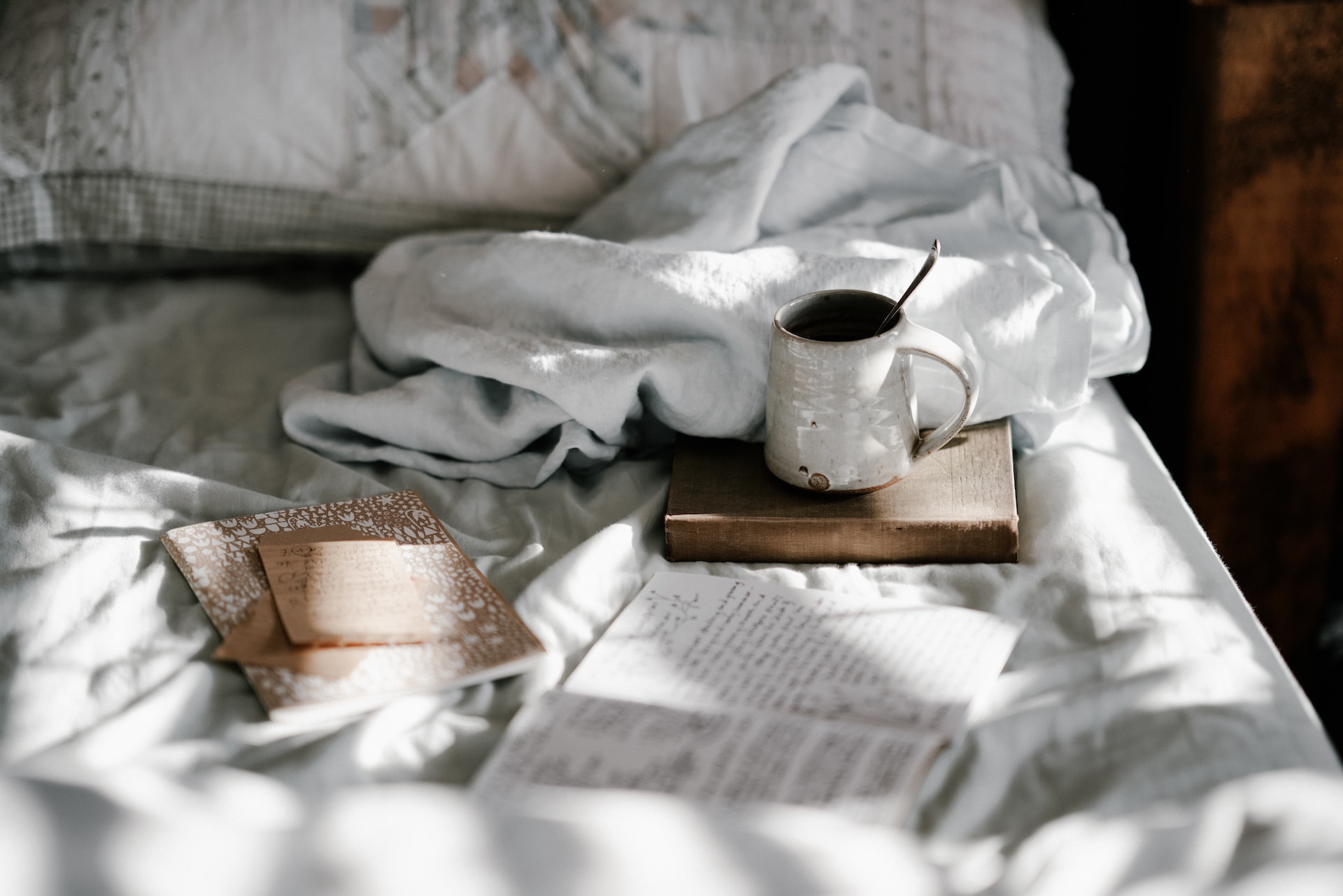 A cup of coffee and book on a bed