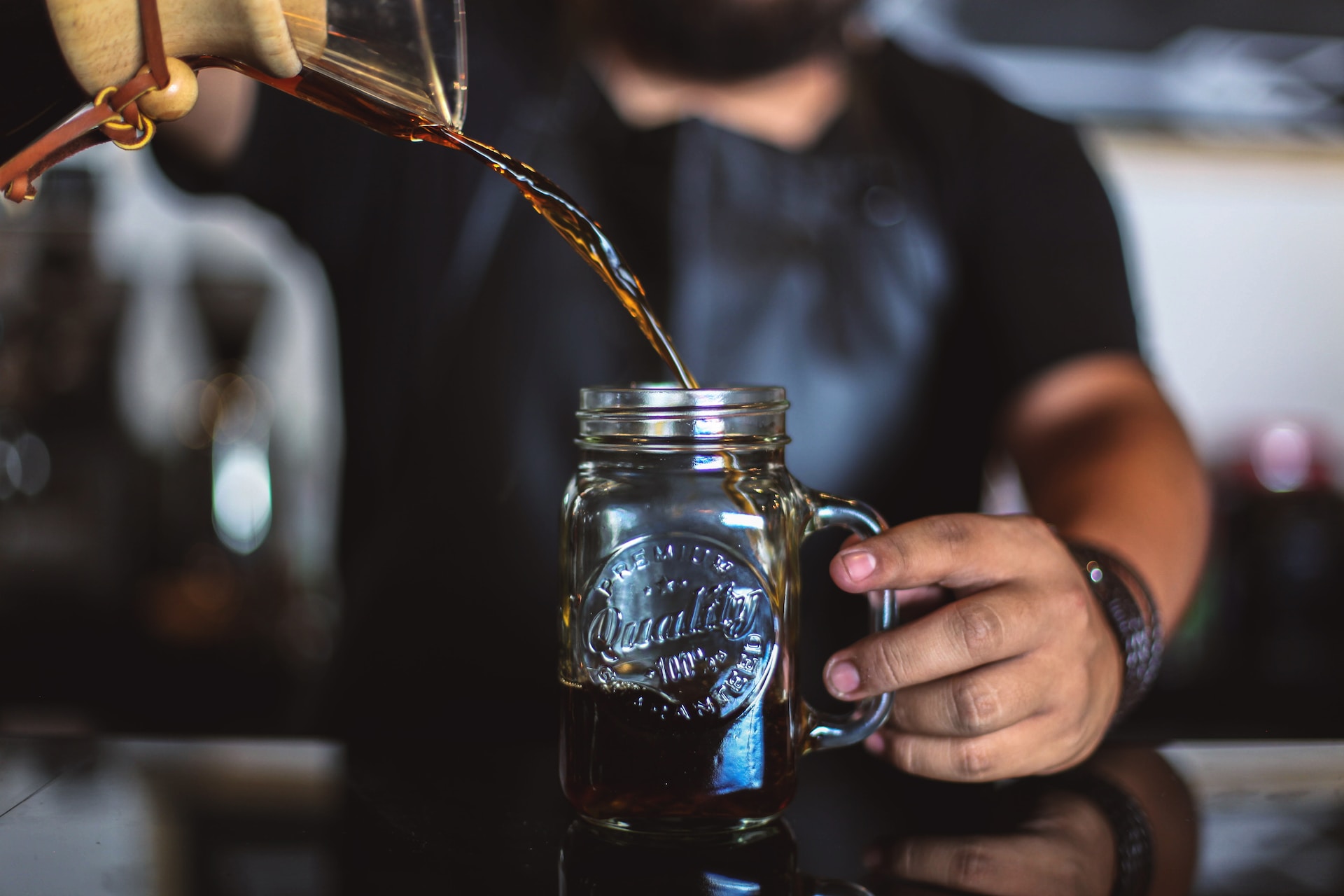 A barista pouring coffee into a glass cup