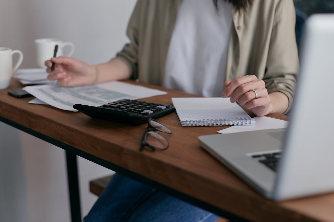 Woman at desk with laptop, calculator and notepads