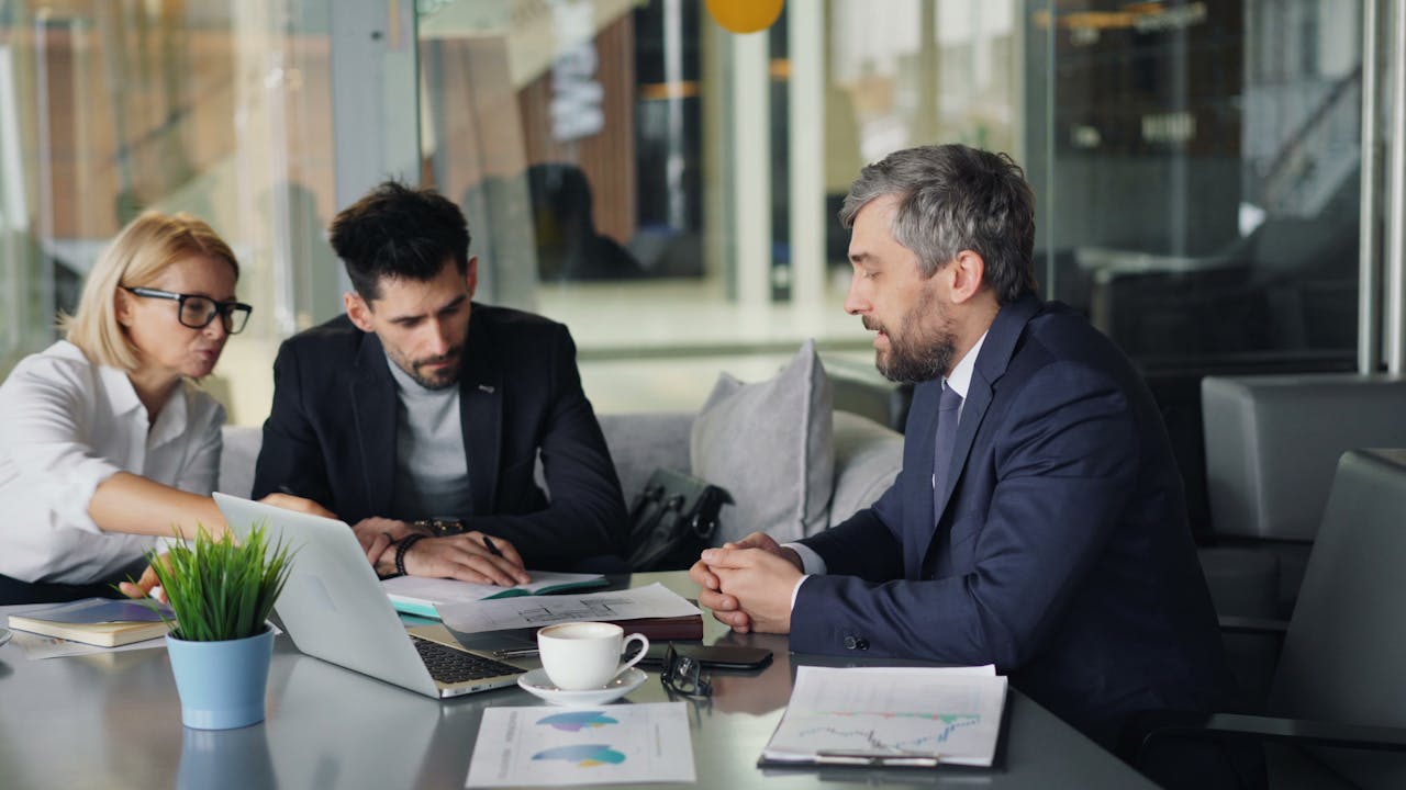 Three people looking at a laptop in a meeting