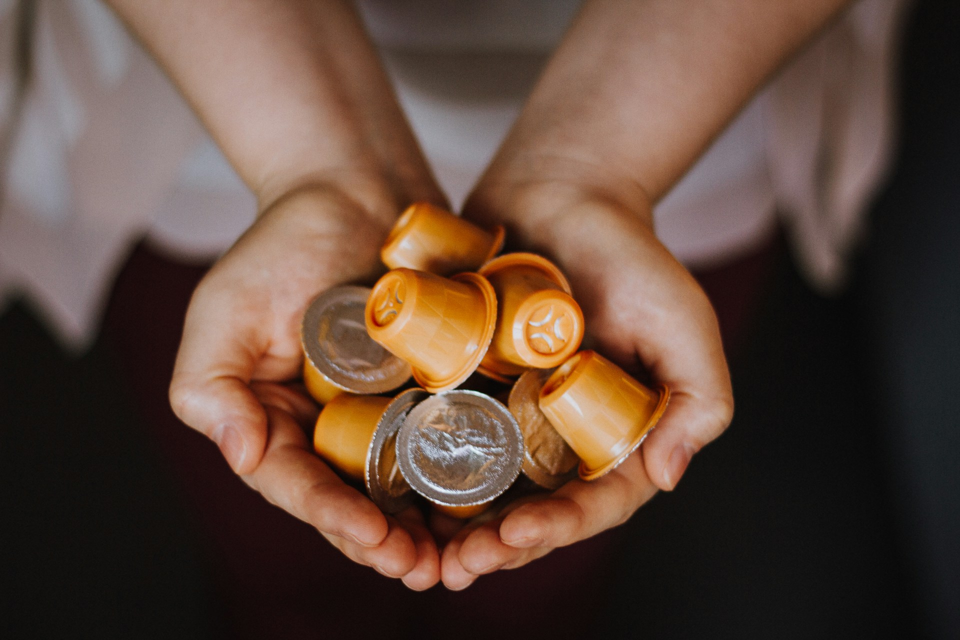 Person holding several coffee pods with orange packaging