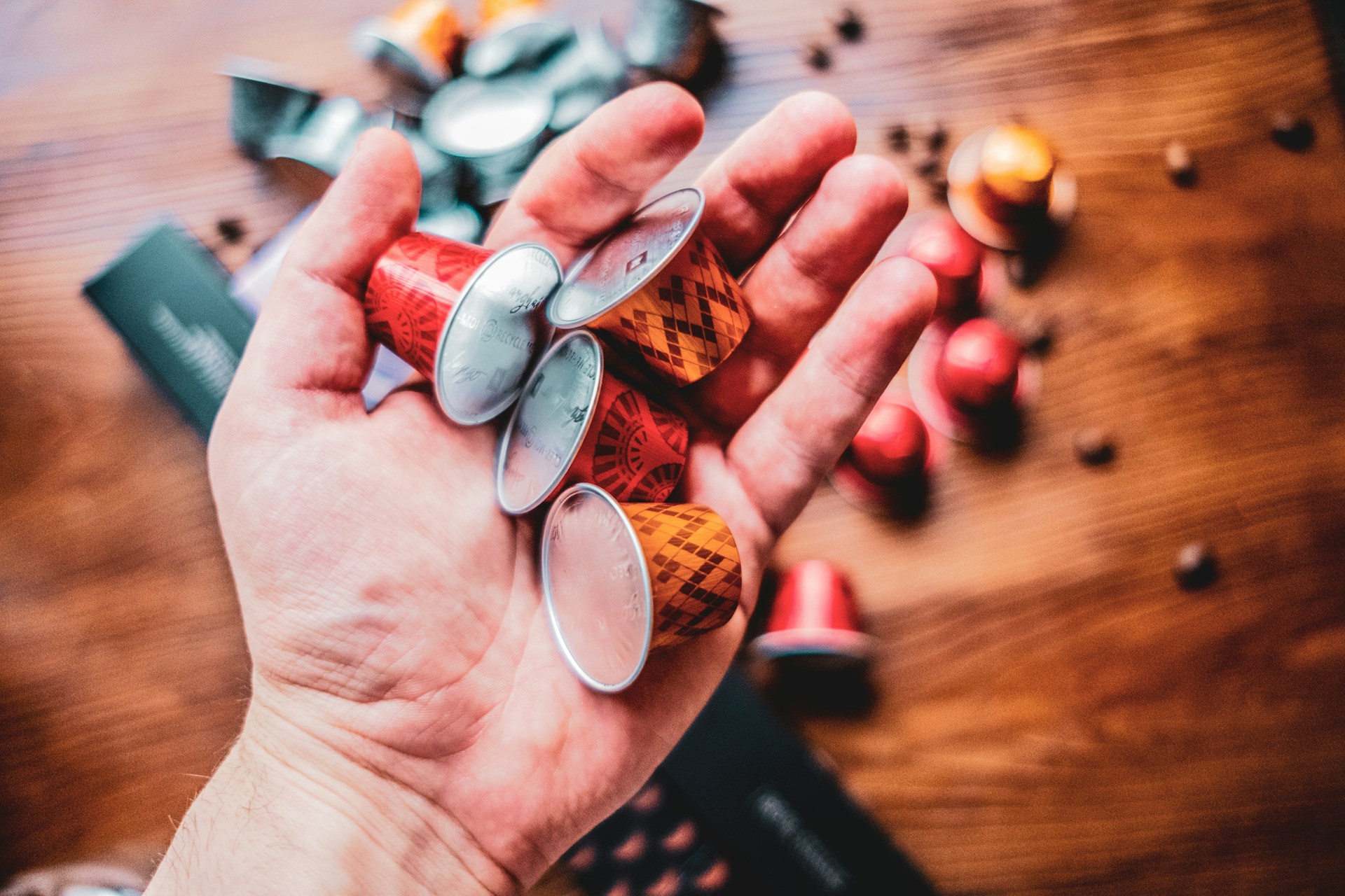 Hand holding coffee pods with more on table below 