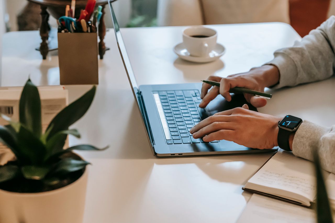 Person typing on laptop and making notes