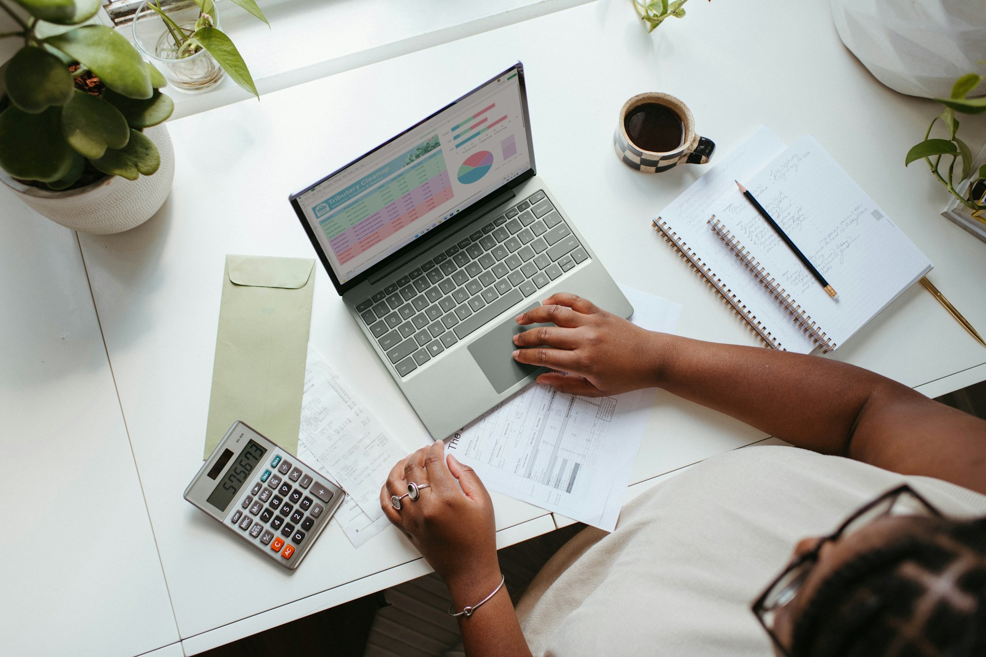 Woman researching on laptop with notebooks and a calculator